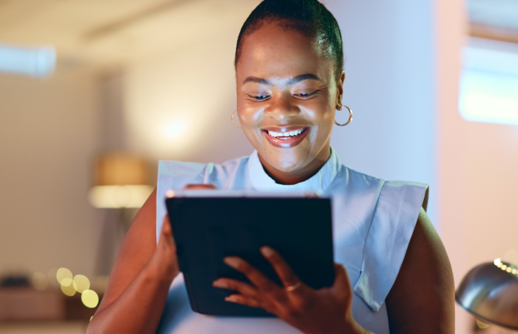 Woman smiling while looking at a digital tablet in an office